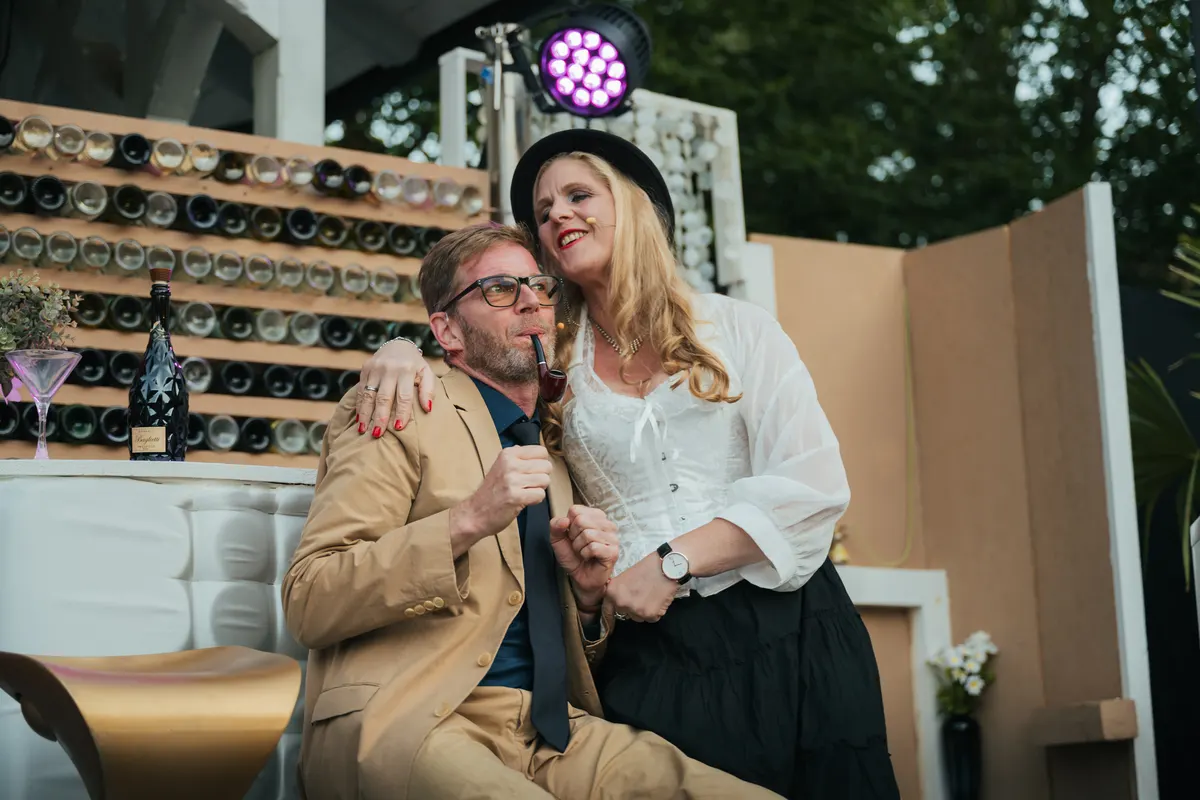 Ein Mann und eine Frau in Abendkleidung sitzen eng umschlungen an einer Bar.